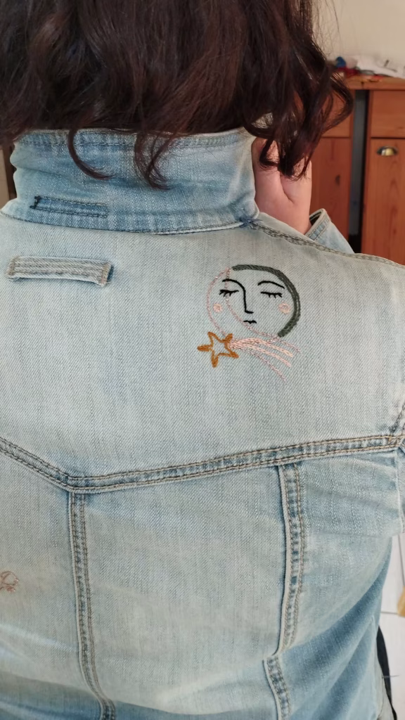 Visage dans la lune brodé sur une veste en jean.
