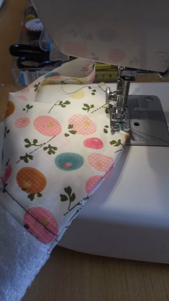 Bavoir sous le pied de la machine à coudre, tissu aux tons pastels.