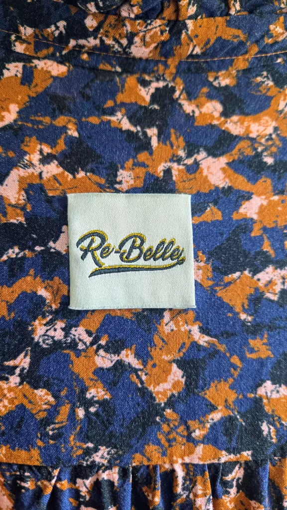 Détail étiquette "Re-belle" sur tissu bleu.