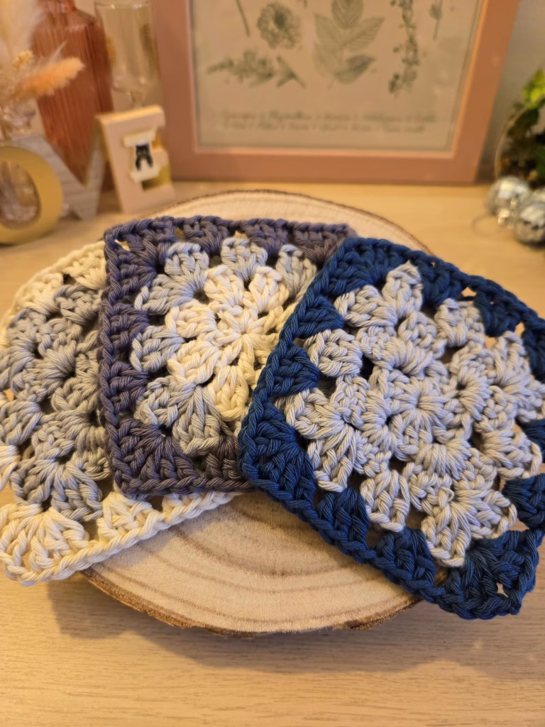 Trois granny squares dans les tons bleu, gris, zinc et naturel.