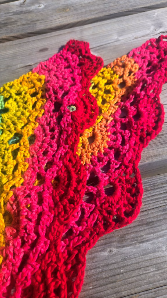 Châle en crochet couleur arc-en-ciel, détail du jaune, orange, rose puis rouge.