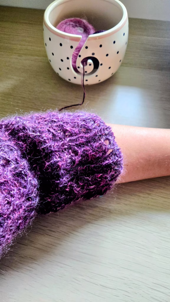 Manche en dentelle en cours de tricot, tons rose et violet.