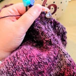 Main qui tiens le tricot, mini aiguilles circulaires en bois, bouchons d'aiguilles en forme de cœur.