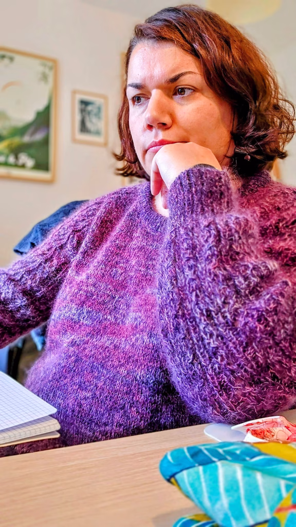 Femme assise à son bureau, pull en tricot.